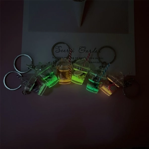 Glow-in-the-dark fruit bubble tea cup keychains with liquid and fruit slices in dark
