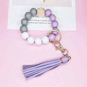 Detail of wooden and silicone beaded wristlet keychain with purple leather tassel and gold ring