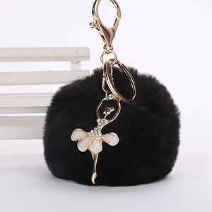 Détail d'un porte-clés pompon en fausse fourrure noire avec une danseuse étoile scintillante