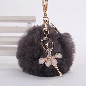 Détail du porte-clés pompon en fausse fourrure gris foncé avec pendentif ballerine dorée