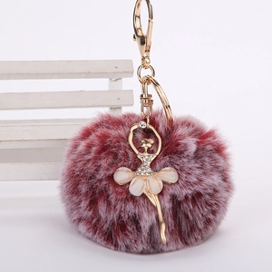 Détail du pompon en fausse fourrure bordeaux avec charm ballerine dorée et strass brillants