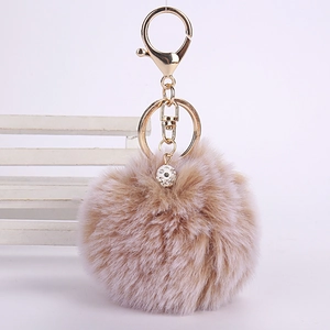 Close-up of a fluffy beige faux rabbit fur ball keychain with sparkling rhinestone beads