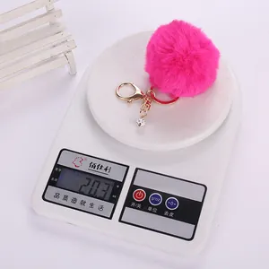Pink faux rabbit fur keychain with crystal ball pendant weighing 20.3g on a scale