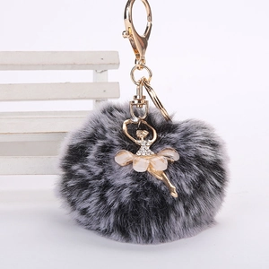 Détail du porte-clés en fausse fourrure grise avec un pendentif de danseuse doré