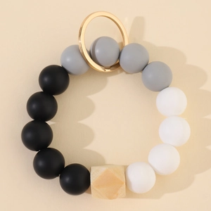 Flat lay of silicone and wood bead keychain with black, grey, white beads and gold metal ring
