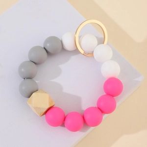 Silicone and wooden bead keychain bracelet with gold metal ring on a grey display block