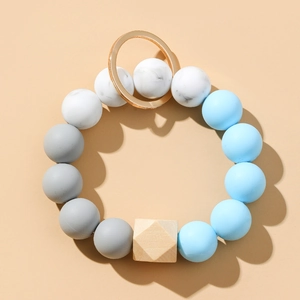 Détail des perles en silicone bleu et gris et perle en bois sur un porte-clés doré