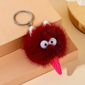 Close-up of fluffy dark red cartoon monster keychain with big eyes and plush texture