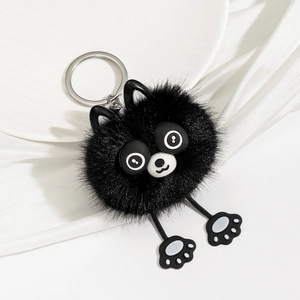 Close-up of black plush animal keychain with cute round eyes on a white silk background