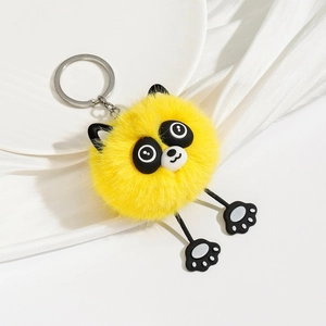 Close-up of fluffy yellow plush animal keychain with cute long legs on white satin silk