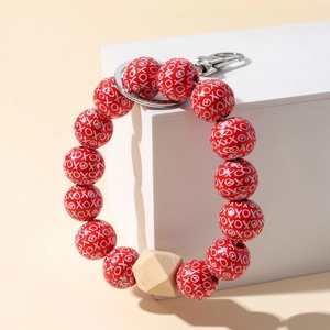 Detail of red beaded keychain bracelet with XOXO heart print and metal lobster clasp