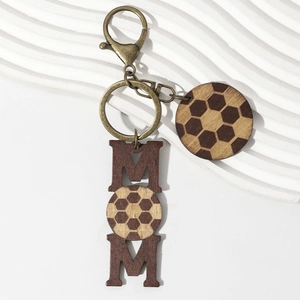 Macro detail of MOM soccer wooden keychain with engraved football pattern and bronze ring