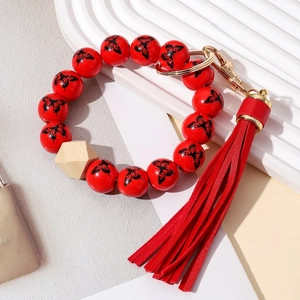 Détail de perles en bois avec papillons, pompon en cuir rouge et fermoir doré du porte-clés