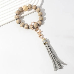Detail of wooden plaid bead keychain bracelet with grey PU leather tassel and gold clasp