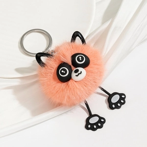 Detail of pink-orange plush cat keychain with long legs on elegant silk surface