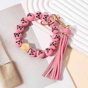 Détail du bracelet porte-clés en perles de bois rose avec pompon en cuir et fermoir doré