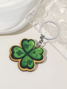 Detail of green four-leaf clover keychain with gold edges and silver metallic ring