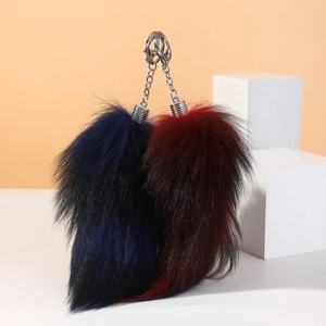 Macro detail of fluffy navy blue and burgundy faux fox fur tail keychains with metal rings
