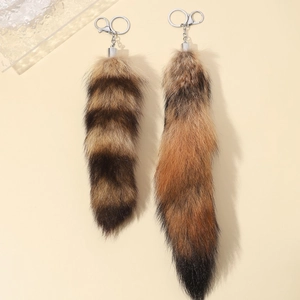 Close-up of fluffy faux fur fox tail keychains in striped brown and reddish-black tones