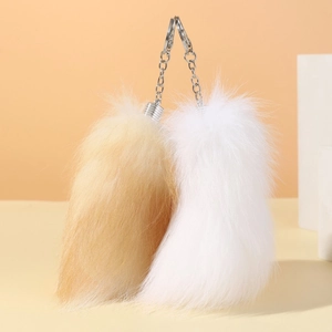 Close-up of fluffy faux fur fox tail keychains in tan and white with silver metal hardware