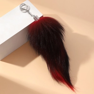 Detailed close-up of large black and red gradient faux fur fox tail keychain with silver clip