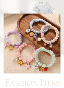 Close-up of macaron color pleated scrunchies with floral and ceramic star pendants