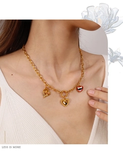 Détail du collier chaîne dorée avec pendentifs cœur, motifs rose, empreinte et lèvres de vampire