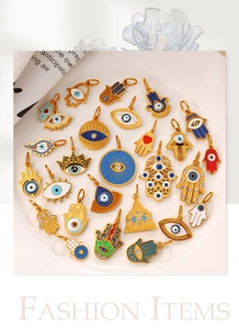 Close-up of gold Hamsa Hand and Evil Eye enamel pendants on a decorative white plate