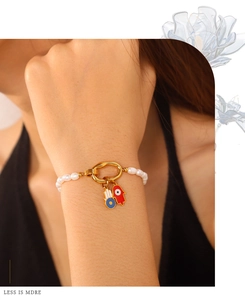 Detail of Hamsa Hand pearl bracelet with colorful enamel charms on model wrist