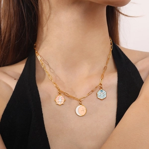 Golden necklace featuring three celestial enamel pendants worn by a model in soft light