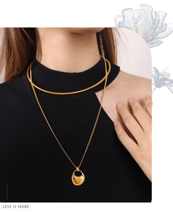 Detail of layered gold snake chain choker and geometric pendant necklace on model