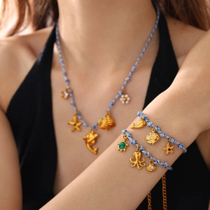 Nautical blue rope jewelry set with gold dolphin, starfish, and turtle charms worn by model