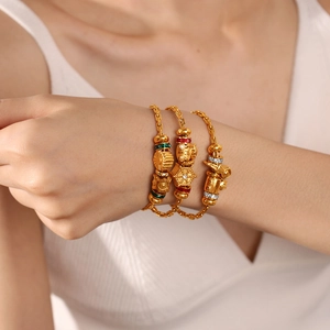 Juego de tres pulseras de cuentas doradas con dijes de girasol en la muñeca de la modelo