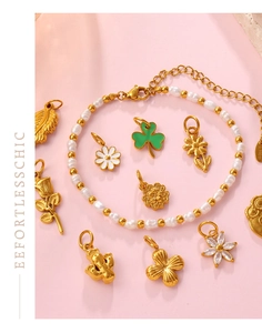 Vista detallada de una pulsera de perlas doradas con colgantes florales sobre fondo rosa