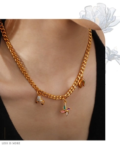 Detail of gold Cuban link necklace with roller skate, windmill and rainbow charms on neck