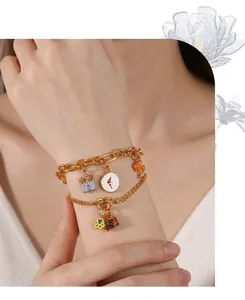 Detail view of double-layered gold charm bracelet with enamel castle and fox on model wrist