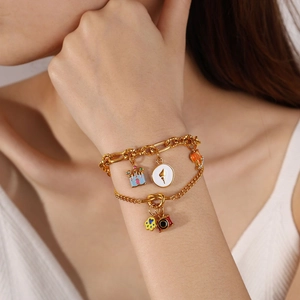 Double-layered gold bracelet with colorful enamel castle and camera charms on wrist