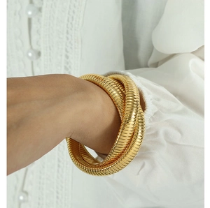 Dettaglio di un bracciale Tubogas flessibile a tre strati placcato oro 18K su manica bianca