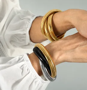 Dettaglio ravvicinato di bracciali a serpente a tre strati placcati in oro 18K su modella