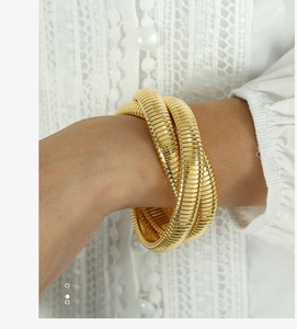 Vista dettagliata di un bracciale Tubogas a tre strati placcato oro su un polso femminile