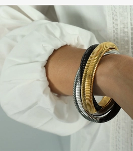 Dettaglio di bracciali a tre strati con trama a squame di serpente in oro, argento e nero