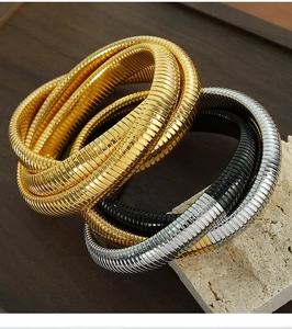 Primo piano di bracciali a tre strati in acciaio al titanio, finiture oro, argento e nero