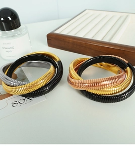 Dettaglio dei bracciali tubogas a tre colori con maglia a serpente in finitura oro e nero