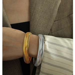 Close-up of flexible Tubogas style stretch bracelets in gold and silver finish on a model