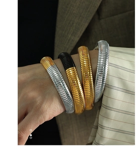 Stack of gold and silver snake bone bracelets showing a textured spiral metal surface