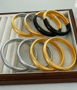 Macro detail of elastic Tubogas snake bracelets in gold, silver and black steel finishes
