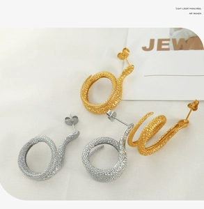 Dettaglio di orecchini a cerchio a serpente in oro e argento con trama a scaglie e stile chic