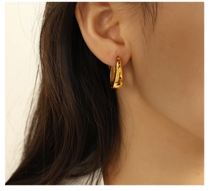 Gros plan de boucles d'oreilles créoles dorées en forme de U portées par un mannequin