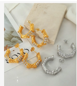 Detailed macro view of gold and silver bamboo-style C-shape earrings with inlaid crystals