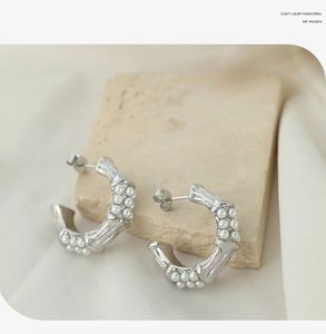 Detailed macro view of silver bamboo texture earrings with inlaid pearls on stone